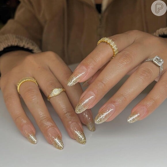 Esmalte com glitter dourado é uma pedida certeira para as unhas no Réveillon: esse formato é o amendoado
