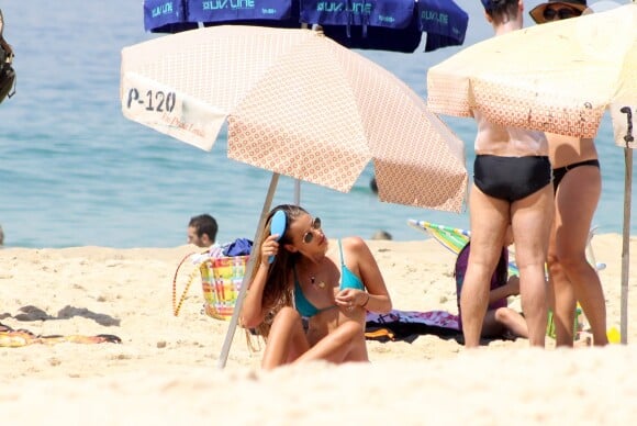 Yasmin Brunet penteia os cabelos enquanto toma sol na praia de Ipanema