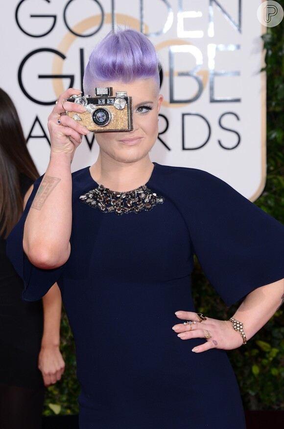 Globo de Ouro 2015: Kelly Osbourne brinca com a bolsa em forma de câmera fotográfica ao posar no tapete vermelho