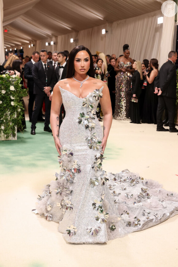 Demi Lovato impressionou com um vestido prateado com detalhes florais enquanto posava no tapete vermelho