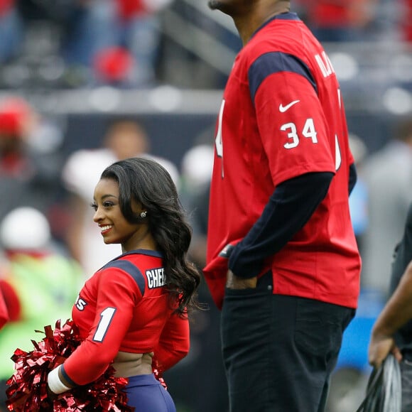 Simone Biles, ao lado do gigante jogador de basquete Hakeem Olajuwon. Ele mede 2,13 metros! 