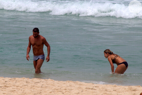 Henri Castelli se exercita com a namorada e mostra boa forma em mergulho na praia da Barra da Tijuca, no Rio