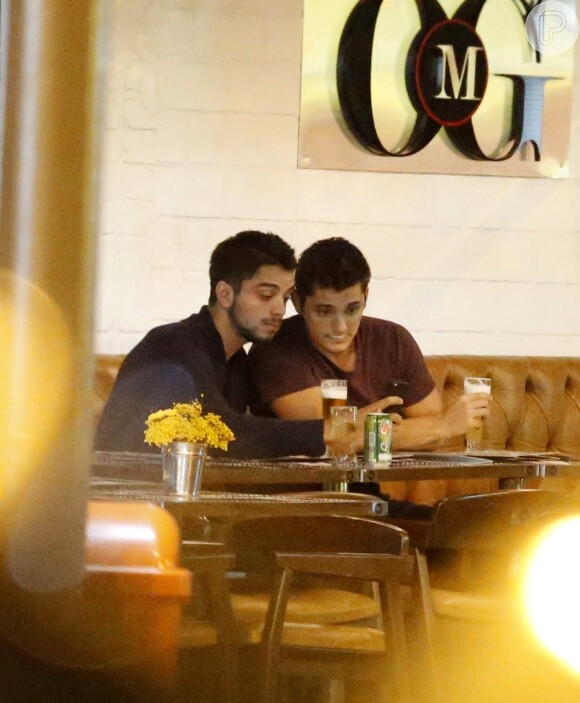 Rodrigo Simas e Bruno Gissoni conferiram a foto que tiraram durante encontro em bar carioca
