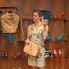 Letícia Spiller posa entre sapatos, jaquetas e bolsas, no coquetel de inauguração da loja Carmim