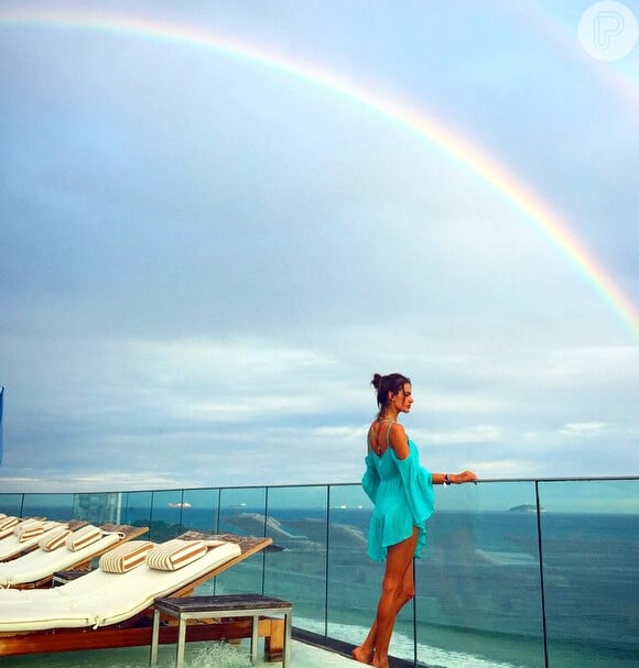 Alessandra Ambrosio posa em outro dia na mesma piscina. Ao fundo, um arco-íris compõe a paisagem