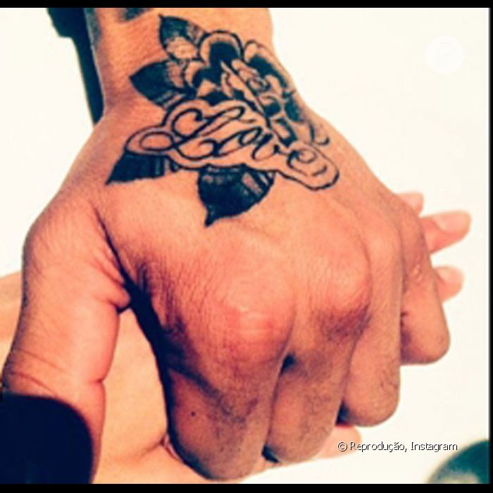 O casal de mãos dadas e a tatuagem do jogador escrito &quot;Love&quot;