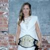 Em ensaio para a marca UFC, Ronda Rousey usou um vestido e jaqueta da marca BCBG. Para arrematar o look, ela vestiu um scarpin, também branco, da grife House Of CB