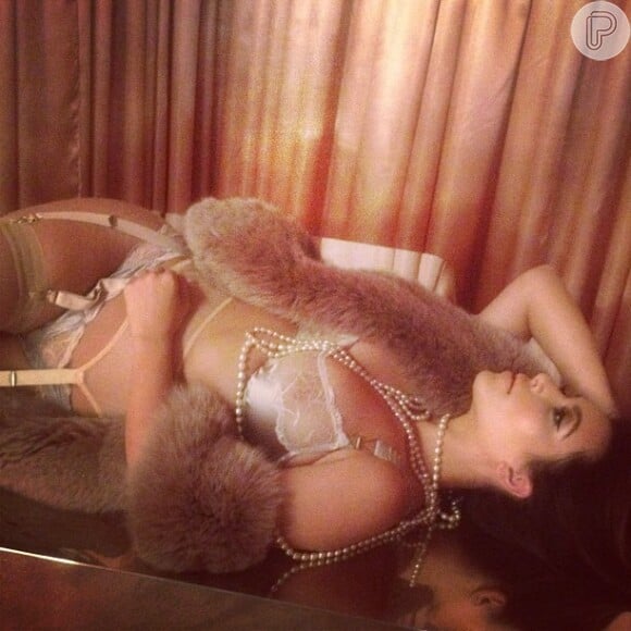 Kim Kardashian também apareceu de cinta-liga, colar de pérolas e casaco de pele, em pose sensual