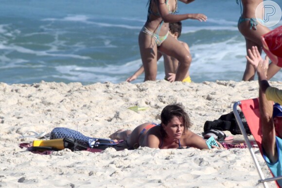 Deborah Secco ficou deitada na areia se bronzeando