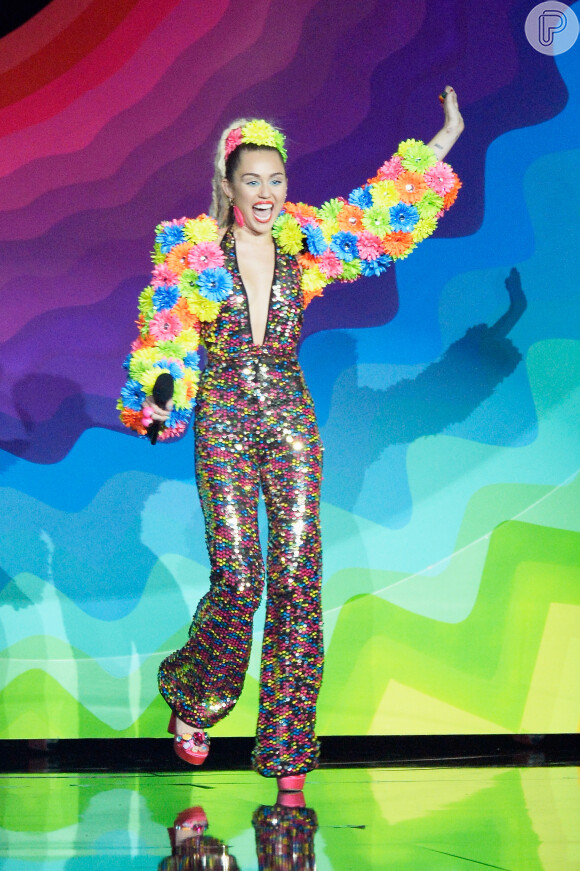 Apresentadora do VMA 2015, Miley Cyrus apostou em diferentes looks para a premiação, como este macacão colorido e com mangas de flores