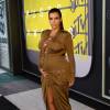 Aos seis meses de gravidez, Kim Kardashian escolheu um look que deixou todas as suas curvas em evidência para o VMA 2015. A socialite usou vestido longo marrom Balmain, com detalhe no decote de amarrações e uma grande fenda central nas pernas