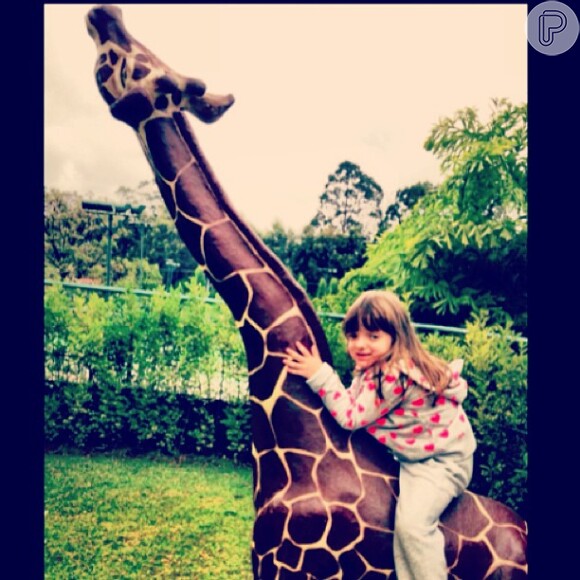 A fofurinha montou em cima de uma girafa, de mentirinha, durante passeio feito em junho deste ano