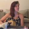 Sophia Abrahão toca violão, enquanto sua cadela tenta subir em seu colo