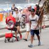Mariana Gross caminha pela orla da praia do Leblon, no Rio de Janeiro, ao lado do marido e do filho, Antonio