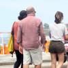 Mariana Gross caminha pela orla da praia do Leblon, no Rio de Janeiro, ao lado do marido e do filho, Antonio