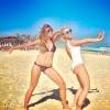 Brincando na praia com amiga, Nattália Rodrigues posa com maiô branco de costas de fora