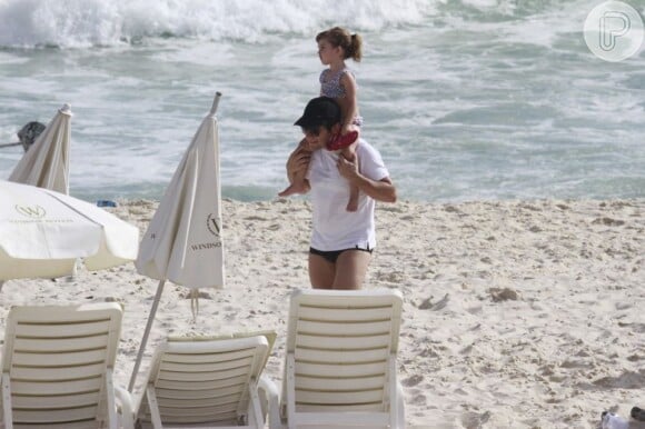 Daniel carrega a filha mais velha, Lara, nos ombros em praia carioca