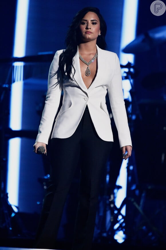 No palco do Grammy Awards, Demi Lovato apostou em calça preta e tailleur branco com decote, nesta segunda-feira, 15 de fevereiro de 2016