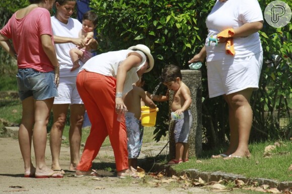 Matheus brinca na bica do parque com a ajuda da mãe e da babá