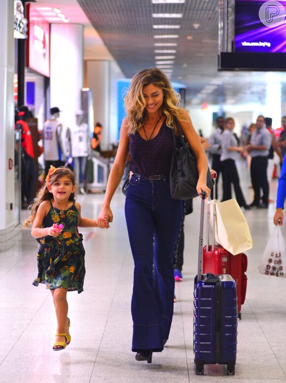 Grazi Massafera usou uma calça jeans Amapô, regata e botas preta para viajar com a filha Sofia, de 3 anos
