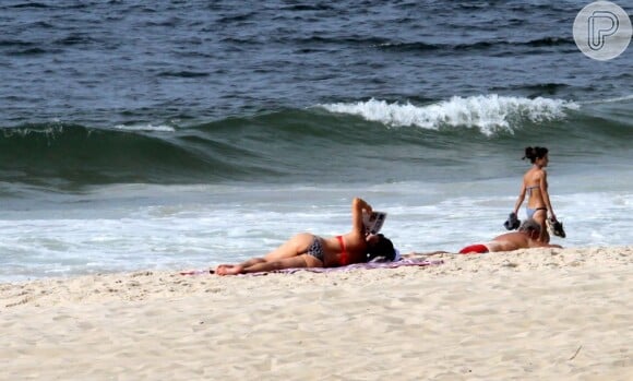 Luiza Brunet lê o jornal deitava na praia