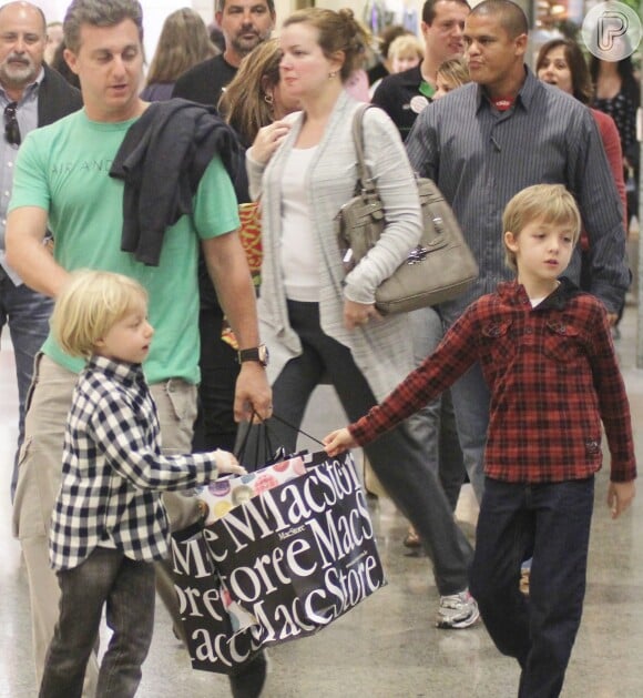 Benício e Joaquim passeiam com o pai, Luciano Huck, no shopping e ajudam a carrega a sacola