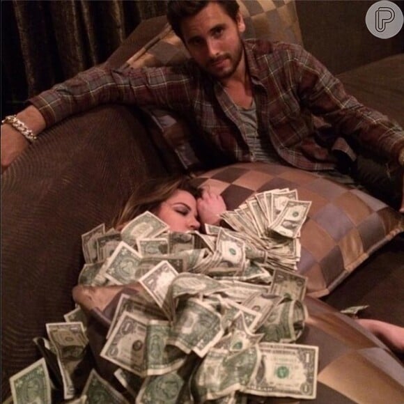 Khloé Kardashian posa coberta de dinheiro após ser acusada de fraudar fundo de caridade, em 21 de novembro de 2013