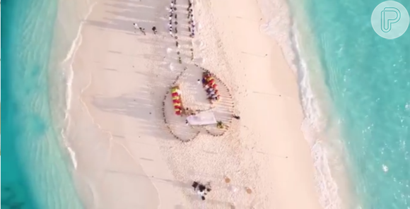 No chão da praia, um coração foi formado com a decoração do casamento