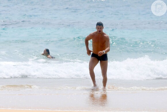 José Loreto corre em direção de Débora, que se bronzeia na areia da praia