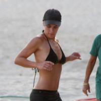 Carolina Dieckmann exibe barriga sarada durante exercícios em praia do Rio
