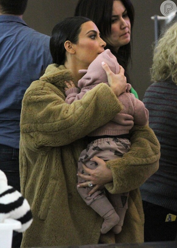 Kim Kardashian espera o embarque com a filha, North West, no colo