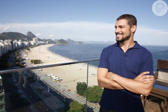 Cauã Reymond posa sorridente para fotos com a paisagem do Rio de Janeiro no fundo