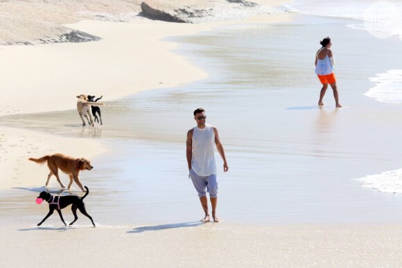 Ricky Martin caminha pela areia da praia do Diabo com cachorrinhos