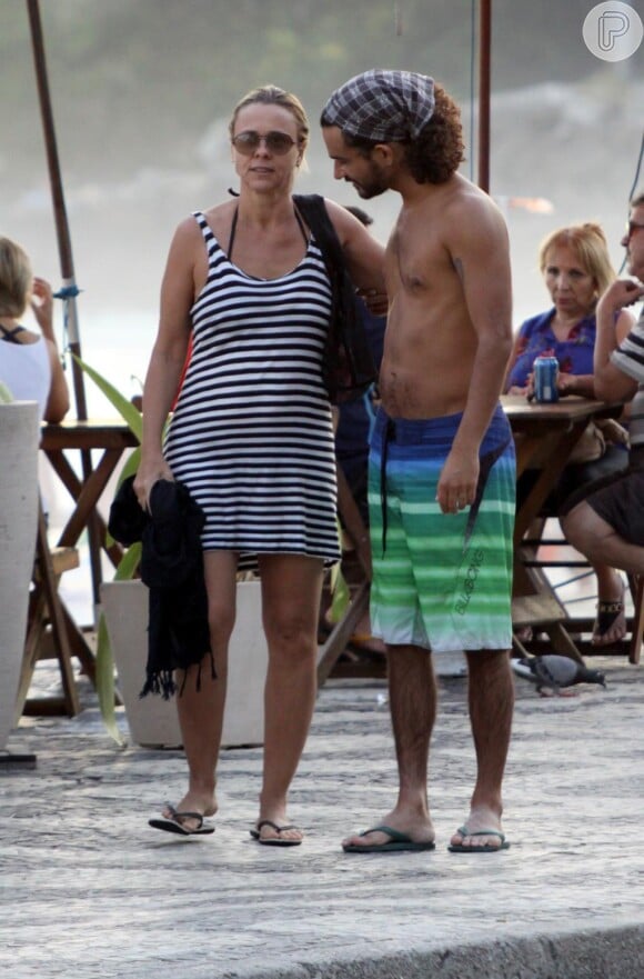 Giulia Gam caminha na praia com o namorado, Flávio Abreu, no Rio