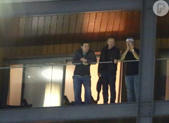 Russell Crowe fuma na sacada de hotel ao lado de amigo e segurança