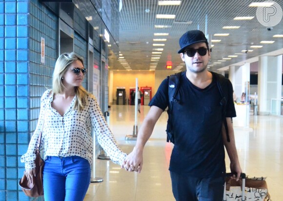 Louise D'Tuani e Eduardo Sterblitch caminham de mãos dadas pelo aeroporto Santos Dumont