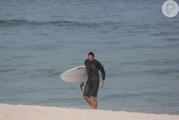 Vladimir Brichta carrega a prancha depois de surfar no mar da Barra da Tijuca, no Rio