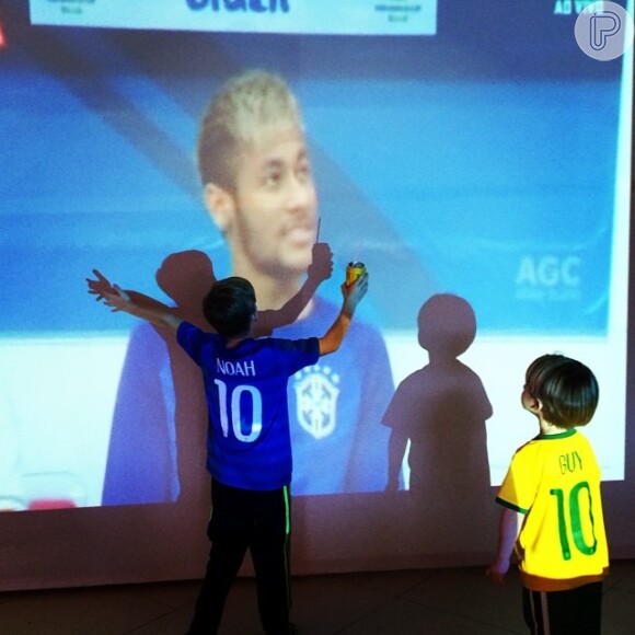 Danielle Winits compartilhou uma fotos dos filhos, Noah e Gay, curtindo o último jogo do Brasil na Copa diante do telão: 'Amor incondicional. Vestindo a camisa. Ontem, hoje, sempre. Neymar feliz filhos felizes. A gente acredita e amarra o amor na chuteira'