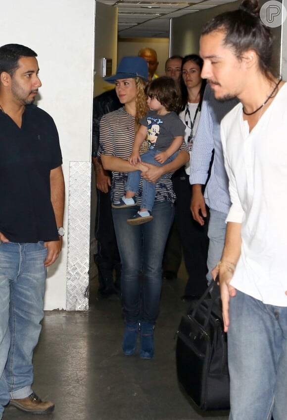 Shakira combinou o chapéu com blusa listrada, calça jeans skinny e botas de salto alto azuis