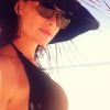Alinne Moraes usou um chapéu de palha azul durante as férias para contar aos seguidores sobre sua gravidez
