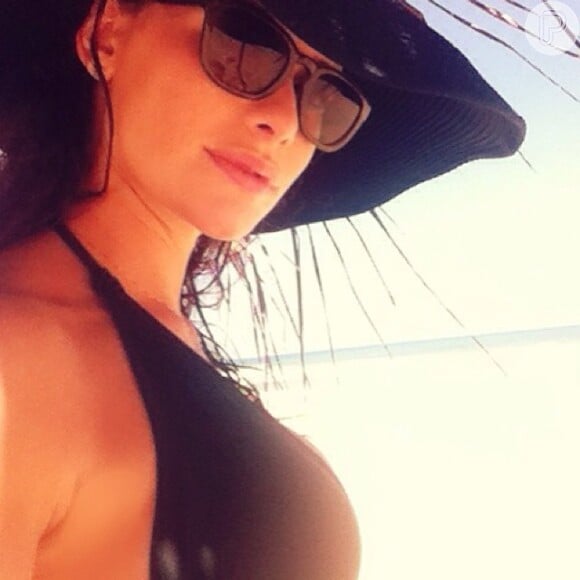 Alinne Moraes usou um chapéu de palha azul durante as férias para contar aos seguidores sobre sua gravidez