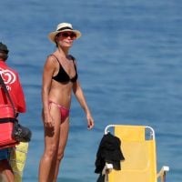 Carolina Ferraz vai à praia com o namorado e exibe barriga chapada