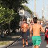 De óculos escuros e sem camisa, Sandro Pedroso corre na orla da Barra da Tijuca, no Rio