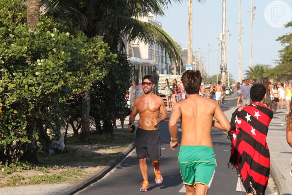 De óculos escuros e sem camisa, Sandro Pedroso corre na orla da Barra da Tijuca, no Rio