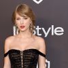 Ombros de fora: Taylor Swift apostou no vestido preto com mangas caídas nas laterais dos ombros e mechinha solta no cabelo