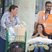 Após alta, Claudia Rodrigues desembarca com cadeiras de rodas e sorridente no RJ