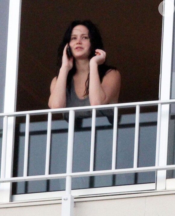 Jennifer Lawrence aparece sem maquiagem e falando no celular em varanda de hotel