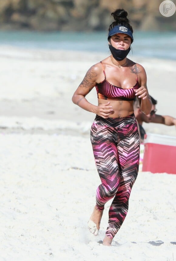 Aline Riscado corre em areia da praia com conjunto de top e legging colorido e de estampa geométrica
