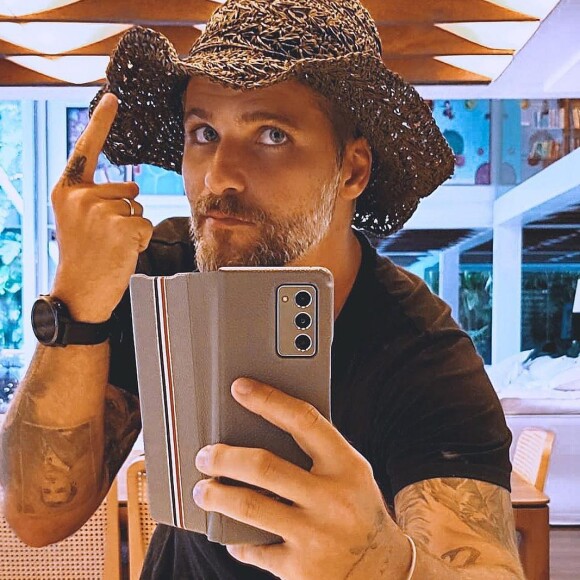 Bruno Gagliasso combina camiseta preta e chapéu de praia para visitar rancho