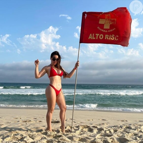 Naiara Azevedo posou com biquíni de top fixo ao lado de bandeira na praia do Rio